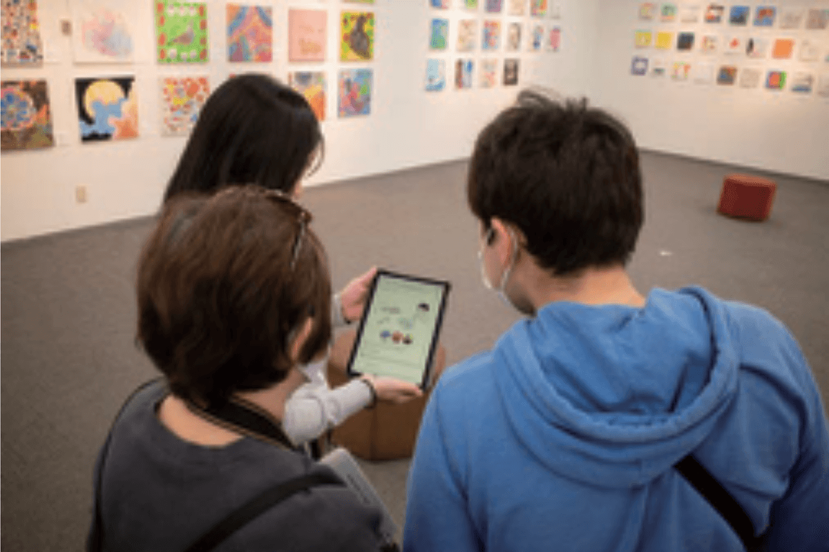 展覧会会場でスタッフとアーティストがタブレットを見ている様子